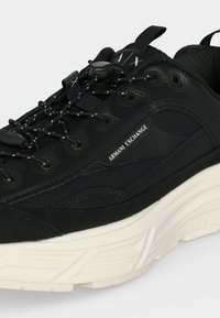 Μαύρο sneaker Armani Exchange με υφασμάτινο πάνω μέρος, επωνυμη πλαϊνή επιφάνεια, κορδόνια με ρυθμιστή και παχύ λευκό πάτο.