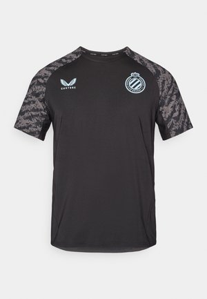 T-shirt de sport noir avec des manches grises à motifs. Il présente un col rond, un logo de club sur la poitrine et un logo de marque sur l'épaule.