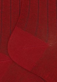 Rote, gerippte Socken mit glatter Textur, leichtem Glanz und verstärkten Zehen, durchzogen von vertikalen Linien im gesamten Stoff.