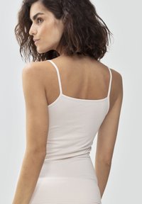 Jasno beżowy top na ramiączkach z cienkimi paskami, wykonany z miękkiego, elastycznego materiału. Posiada dopasowany krój, który podkreśla górną część ciała.