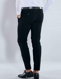 Schwarze Hose mit schmaler Passform, strukturiertem Stoff, Seitentaschen und Details an der Gesäßtasche, kombiniert mit schwarzen eleganten Schuhen.