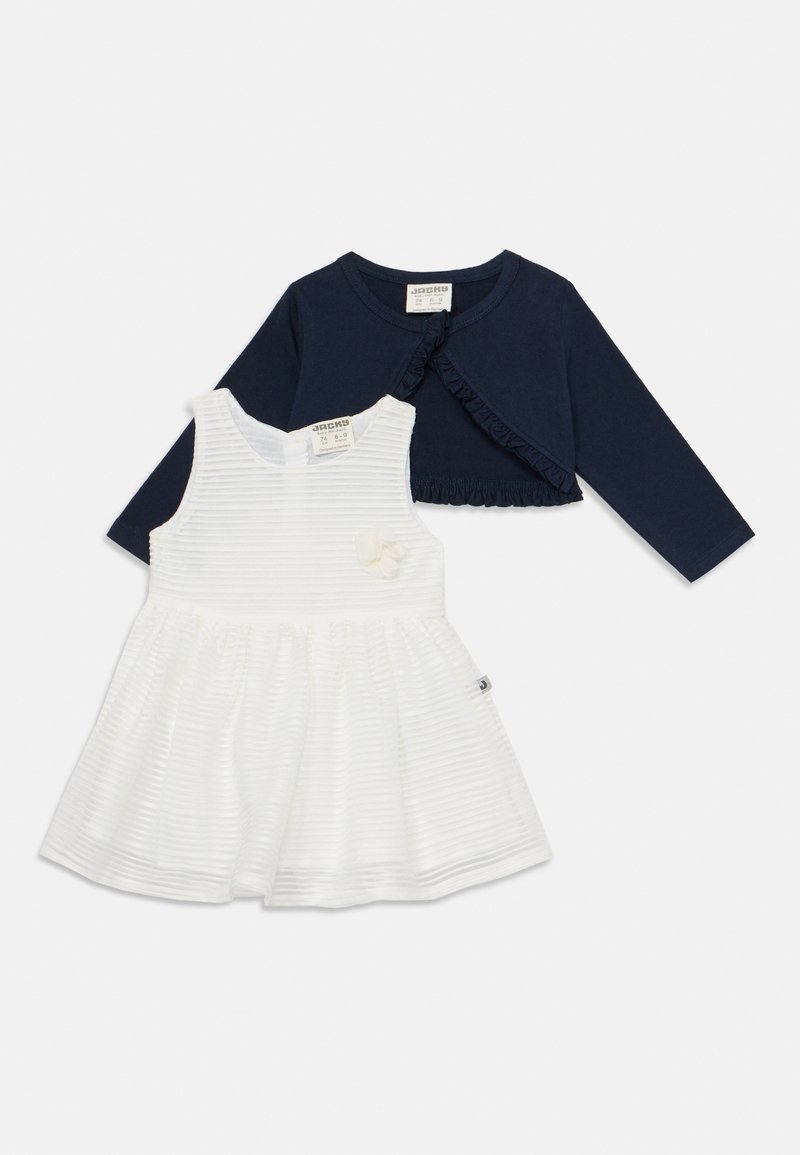 Ναυτικό μπλουζάκι μακρυμάνικο με φούσκες και λευκό φόρεμα με ρίγες που διαθέτει ανθισμένο διακοσμητικό και φούστα σε καμπυλωτό στυλ. Και τα δύο είναι φτιαγμένα από μαλακά υφάσματα.