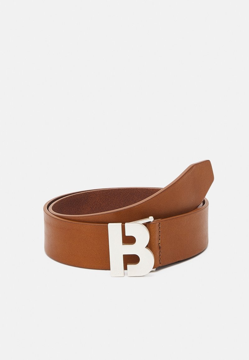 Ceinture en cuir marron avec une boucle en métal argenté ornée d'un design distinctif en forme de "B". Texture lisse avec une forme classique et des accents minimaux.