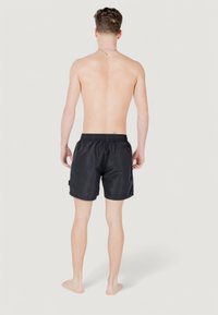 Shorts de baño negros hechos de material ligero, con una cintura elástica, un bolsillo trasero y un corte relajado. Diseño sencillo sin patrones.