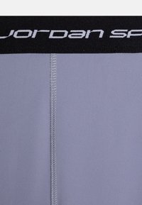 Des sous-vêtements de sport gris avec une ceinture élastique noire arborant le logo « jordan sports » en blanc. Texture lisse avec des coutures à plat.