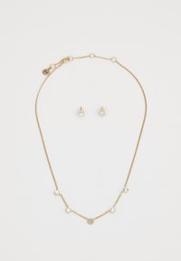 Collana in tono dorato con accenti di cristallo rotondi e un design circolare centrale; abbinata a orecchini a perno coordinati con pietre trasparenti.