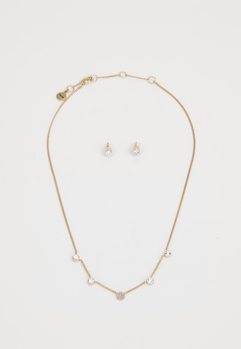 Collana in tono dorato con accenti di cristallo rotondi e un design circolare centrale; abbinata a orecchini a perno coordinati con pietre trasparenti.