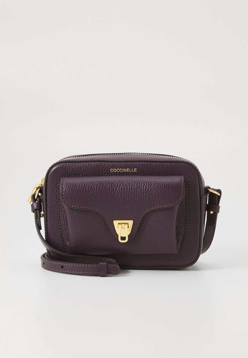 Purple leather crossbody bag with a textured finish, gold hardware, a front pocket, and an adjustable strap. Compact rectangular design.