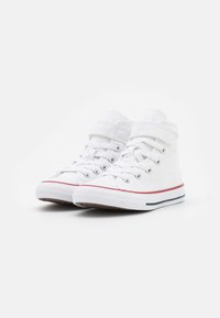 Valkoiset kangaskorkeat sneakerit, joissa on nauha- ja tarranauha kiinnitys, ja niissä on punaisista ja sinisistä raidoista koostuva pohja. Tasainen pinta, pyöreä kärki.