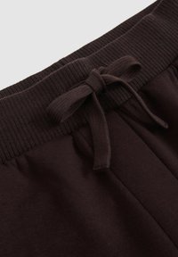 Bruine katoenen joggingsbroek met een geribbelde tailleband en een strikdetail. De stof is zacht met een gladde textuur.
