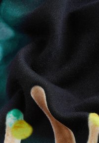 Un tejido negro con una textura suave presenta patrones abstractos y coloridos en tonos de verde, amarillo y beige a lo largo de su superficie.