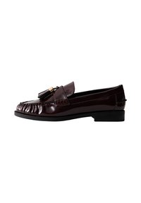 Mocassino in pelle patinata bordeaux con tacco basso, caratterizzato da un design plissettato e dettagli con pon pon sulla vamp. Texture liscia, forma classica.