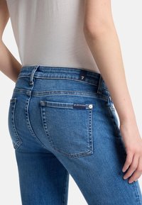 Strakke blauwe jeans met een hoge taille, gemaakt van denim, met een subtiel ontwerp van de achterzak en een klein merketiket op de tailleband.