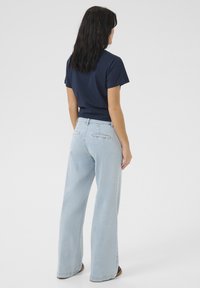 Navy cotton t-shirt, short sleeves, paired with light blue wide-leg jeans. Jeans feature back pockets and a relaxed fit.