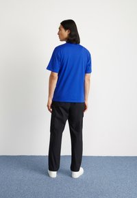 Blue cotton t-shirt with short sleeves; paired with black cargo pants featuring side pockets. White sneakers complete the look.