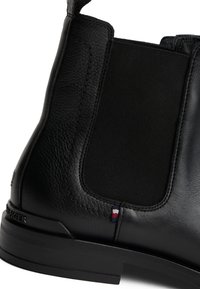 Svart lær ankle boot med elastiske sidepaneler, teksturert finish og gummisåle med logo. Slank moderne design.