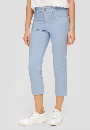 Jean cropped de color azul claro con cintura alta, dos bolsillos frontales y cierre de botón. Llevados con zapatillas blancas sobre un fondo neutro.