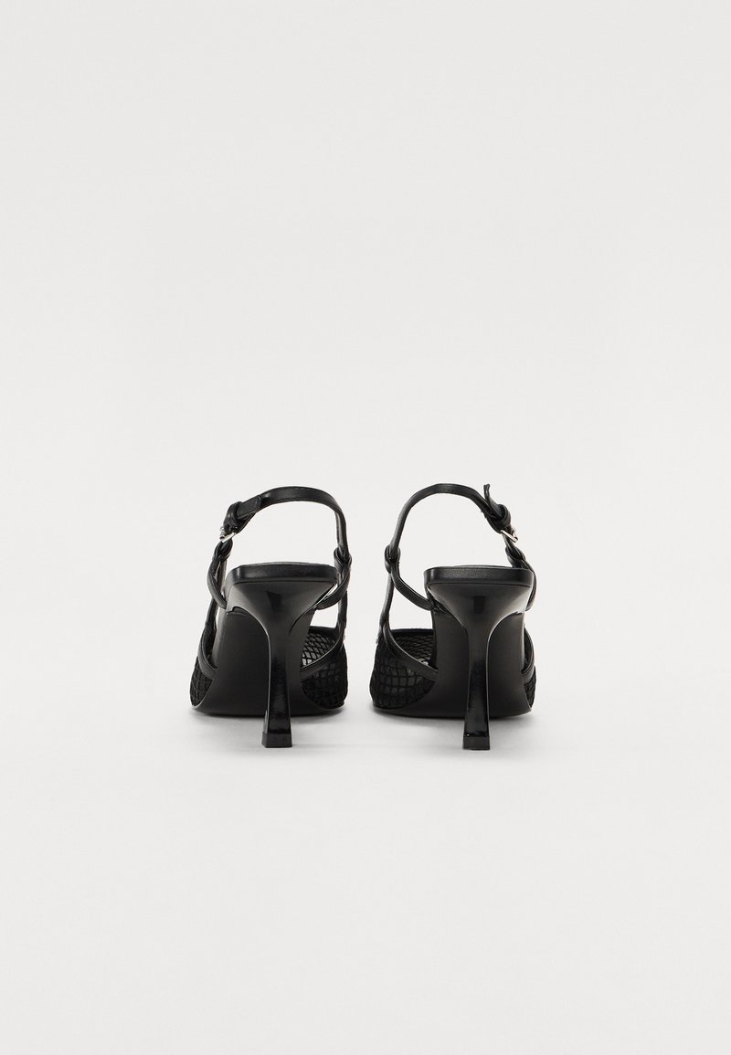 Sandales à talons hauts noires avec un design en maille texturée, dos ouvert et bride à la cheville. Le talon est étroit et élégant, améliorant ainsi la silhouette générale.