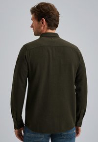 Camisa de franela verde oscuro con mangas largas, puños abotonados y un cuello clásico. Presenta una espalda con yugo y una textura sutil.