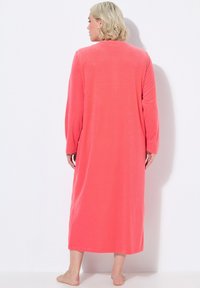Camisón largo color coral, hecho de una tela suave, con mangas largas, un corte holgado y un escote redondo, que llega hasta los tobillos.