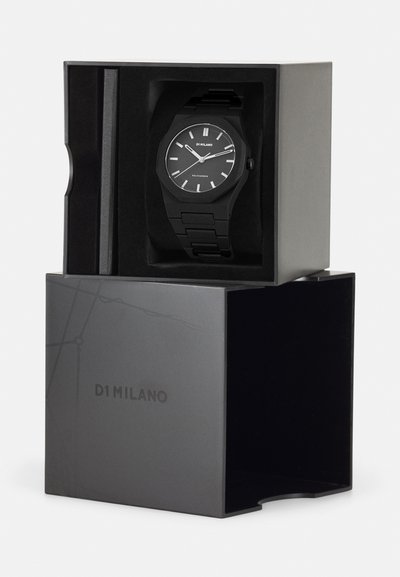 Μαύρο αναλογικό ρολόι με γεωμετρική θήκη και σκούρα λωρίδα, τοποθετημένο σε ορθογώνιο μαύρο κουτί με το όνομα της μάρκας "D1 Milano" ανάγλυφο στην πρόσοψη.