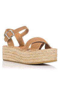 Sandalias de cuña de ante en tono marrón claro con correas cruzadas, detalle de hebilla plateada y suela de plataforma envuelta en yute. Superficie texturizada, diseño de talón abierto.