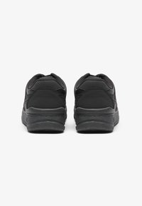 Sapatos atléticos pretos com parte superior em couro liso e malha, colarinho acolchoado e solas de borracha texturizada. Design de perfil baixo com acentos mínimos.