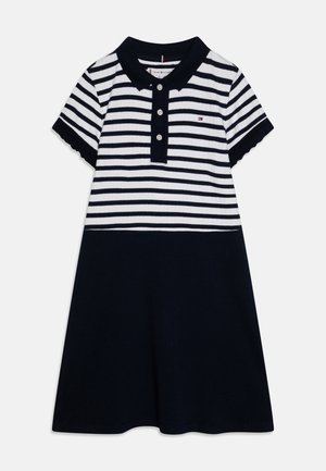 Abito polo con strisce orizzontali blu navy e bianche, maniche corte, chiusura con bottoni e parte inferiore blu navy uniforme. Materiale in cotone morbido, design casual.