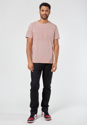 Short-sleeve, red and white patterned t-shirt made of cotton, paired with black slim-fit pants and red-accented sneakers.