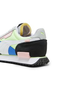 Puma Sneaker mit einem Mehrmaterialdesign in Weiß, Schwarz, Grün und blauen Akzenten, retro Form und strukturiertem Gummisohle.