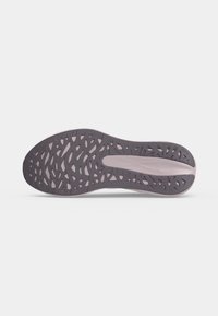 Semelle de chaussure avec découpes de forme organique gris foncé et un soutien central de la voûte plantaire lisse, affichée sur un fond clair uni.