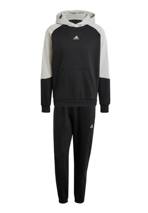 Completo sportivo in nero e grigio composto da una felpa con cappuccio e tasca anteriore e pantaloni jogger. Entrambi i capi presentano polsi elasticizzati e il logo adidas.
