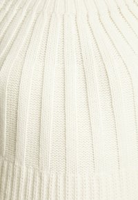 Kreemi värvi kootud sviiter vertikaalse soonikuga tekstuuriga ja sobiva kehaosaga. Omab laia soonikut alläärtes ja pehme, paks kude.