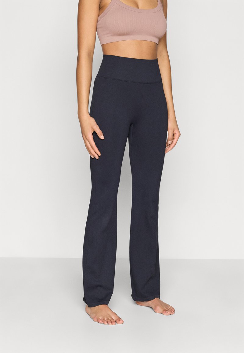 Marinblå utsvängda byxor i stretchigt tyg med mjuk textur och hög midja, kombinerade med en ljusbrun kort topp.