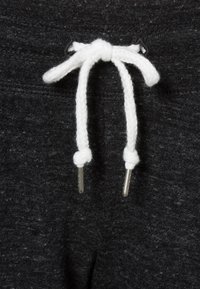 Šedé tepláky mají bílou šňůrku s texturovanými konci. Tkanina má měkký vzhled s jemným melírováním.