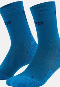 Calze sportive blu con un design a coste texturizzato, caratterizzate da un logo vicino alla parte superiore e una sezione con grip a motivo nella parte inferiore.