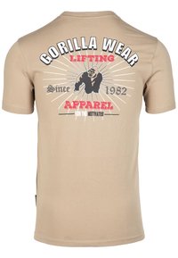 Bežinis medvilninis marškinėliai trumpomis rankovėmis su juodu, raudonu ir baltu grafiniu spaudiniu, vaizduojančiu gorilą ir tekstą apie jėgos treniruotėms skirtą aprangą.