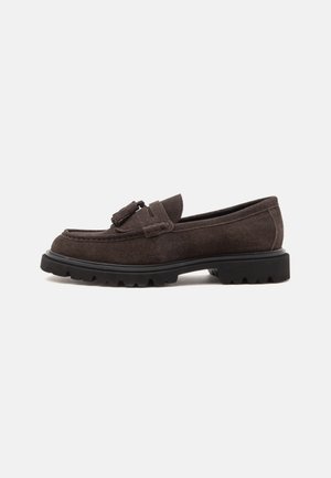 Mocassino in camoscio marrone scuro con nappine e suola spessa in gomma nera con carrarmato, mostrato di profilo su sfondo chiaro.