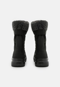 Sorte vanntette støvler med en teksturert suede-ytre, kunstpelskant og gummisole; designet for kalde, våte forhold.