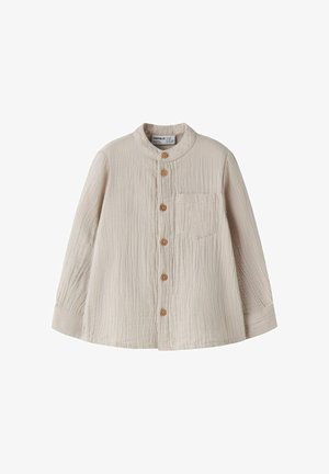 Chemise beige à manches longues pour tout-petit avec col rond, boutons en bois devant, et poche poitrine, fabriquée en tissu texturé.