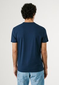 Marineblå T-shirt med korte ærmer lavet af bomuld, med en rund halsudskæring og en glat tekstur. Båret med lyseblå jeans.
