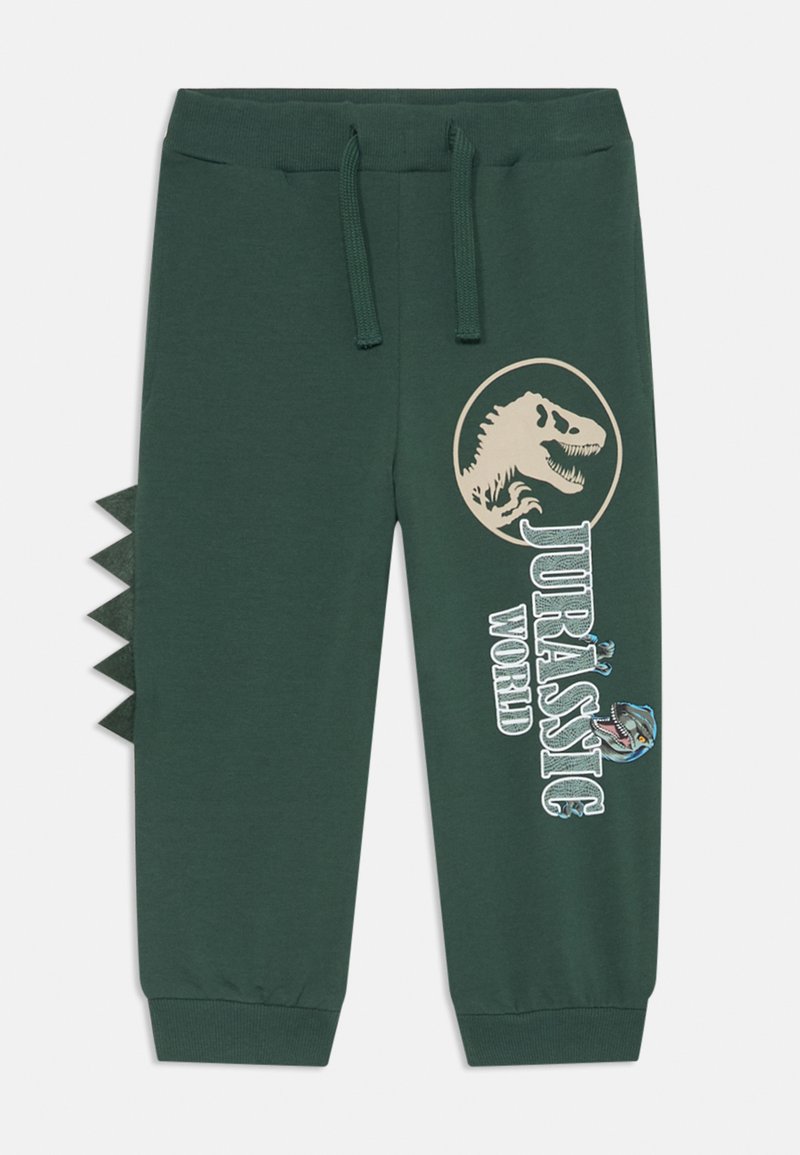 Pantaloni della tuta verdi con vita elastica, grafica di dinosauro e testo "Jurassic World" sul fronte, e spuntoni in tessuto lungo il lato.