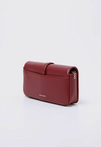 Borsa in pelle artificiale rossa con texture liscia, forma rettangolare, pattina pieghevole e dettaglio in zip argentata. Logo stampato sul davanti.