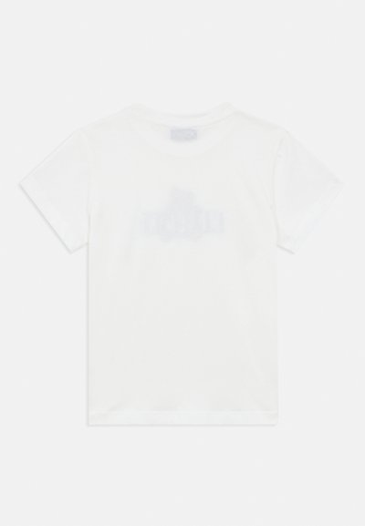 Λευκό παιδικό μπλουζάκι με κοντά μανίκια, εμφανιζόμενο από πίσω, με αχνό κείμενο ή λογότυπο ορατό μέσα από το ύφασμα.