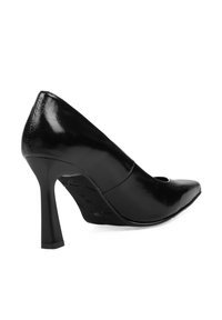 Zapato de tacón alto de charol negro con punta afilada y tacón cuña, con una superficie lisa y brillante y un detalle recortado.