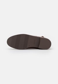 Brown shoe sole with ribbed texture, featuring a smooth rounded shape and manufacturer logo. Number "37" embossed on the side.