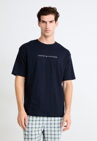 Marineblå bomull t-skjorte med rund hals og korte ermer, med en hvit og rød "TOMMY HILFIGER"-logo over brystet.