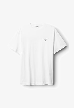 Bela bombažna majica s kratkimi rokavi, ki ima okroglo ovratnik in majhen tisk na levi strani prsnega dela. Gladka tekstura, sproščen dizajn.