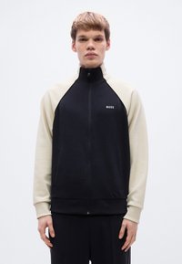 Ζακέτα με κουκούλα και φερμουάρ, με μαύρο σώμα και εκρού μανίκια, κατασκευασμένη από μαλακό ύφασμα με ριμπ μανσέτες και διακριτικό λογότυπο "BOSS".