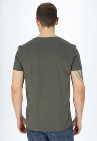Mörk olivgrön t-shirt med kort ärm, tillverkad av bomull och med rund halsringning. Baksidan har en slät textur och en figursydd design.